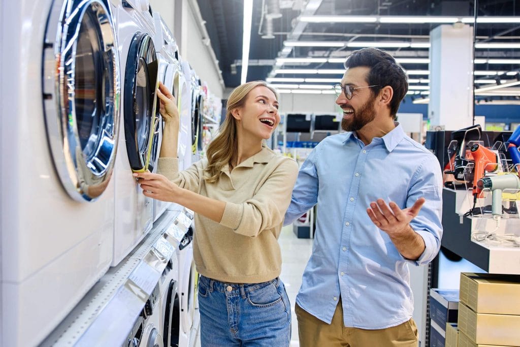 Deux personnes comparant une machine à laver dans un magasin d'éléctromenager