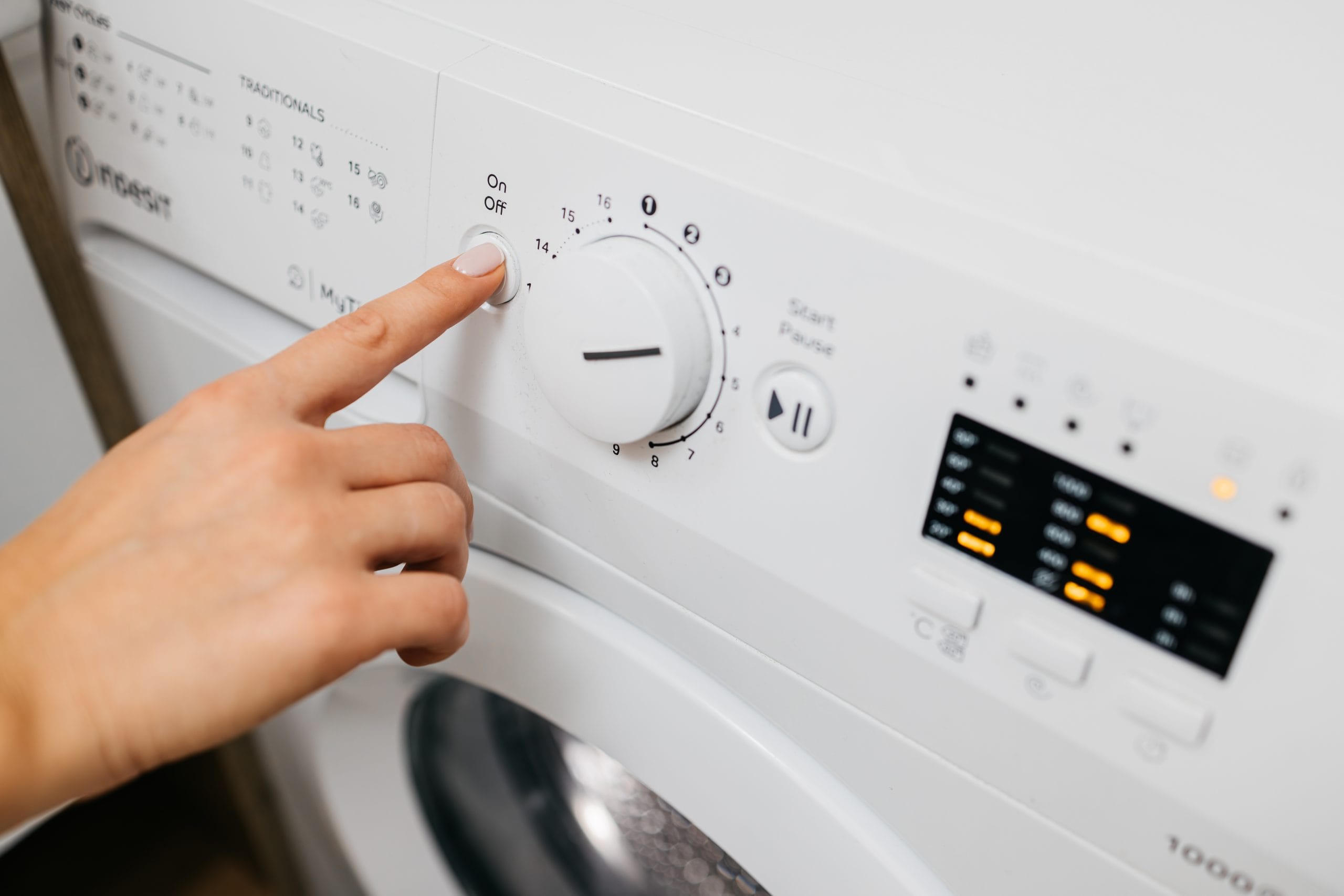 Main réglant le panneau de commande d'un lave-linge